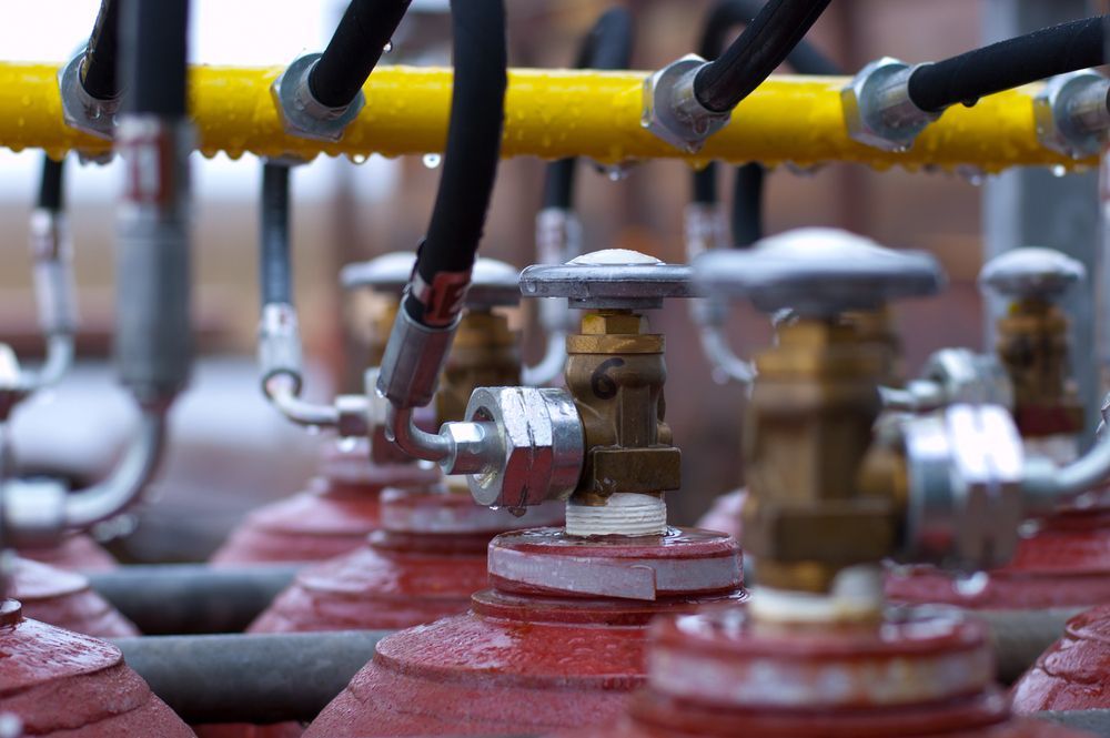 A Row of Red Gas Cylinders Are Lined Up Next to Each Other — FNQ Hot Water In Mareeba, QLD