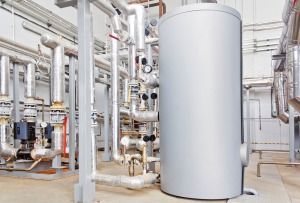 A Large Gray Tank is Sitting in the Middle of a Room Filled With Pipes — FNQ Hot Water In Cairns, QLD