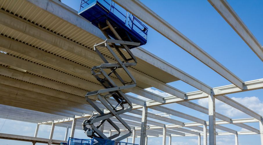 A Blue Scissor Lift is Sitting on Top of a Building Under Construction — FNQ Hot Water In Mareeba, QLD