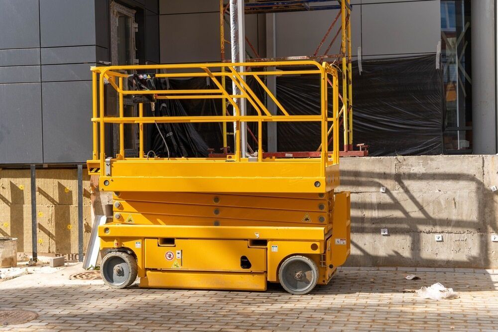 A Yellow Scissor Lift is Parked in Front of a Building Under Construction — FNQ Hot Water In Mareeba, QLD