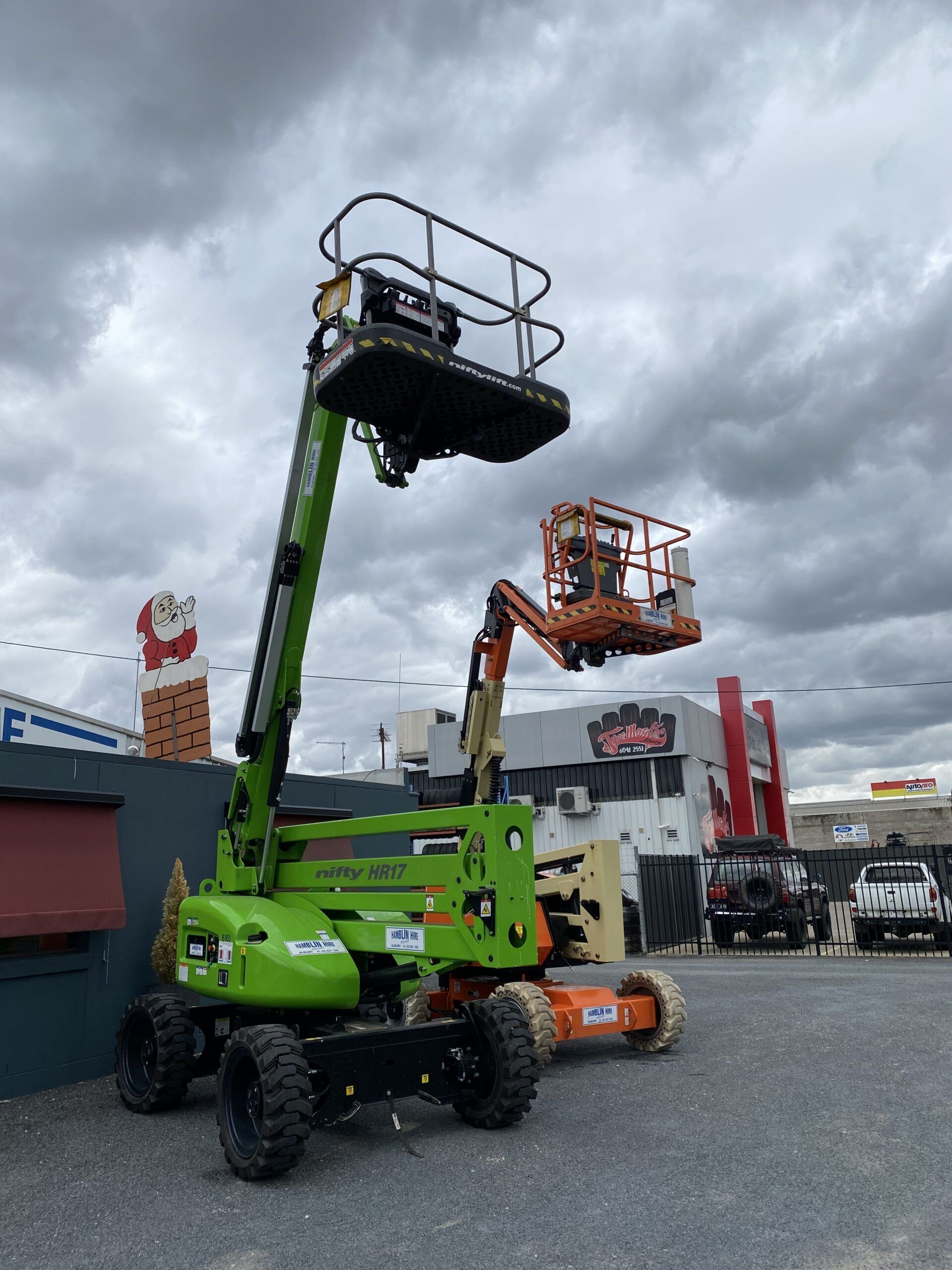 A Green Aerial Lift is Parked in Front of a Building — FNQ Hot Water In Mareeba, QLD