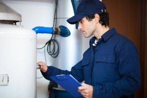 A Man is Holding a Clipboard and Looking at a Water Heater — FNQ Hot Water In Atherton, QLD