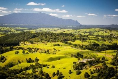 An Aerial View of a Lush Green Landscape With a Mountain in the Background — FNQ Hot Water In Atherton, QLD