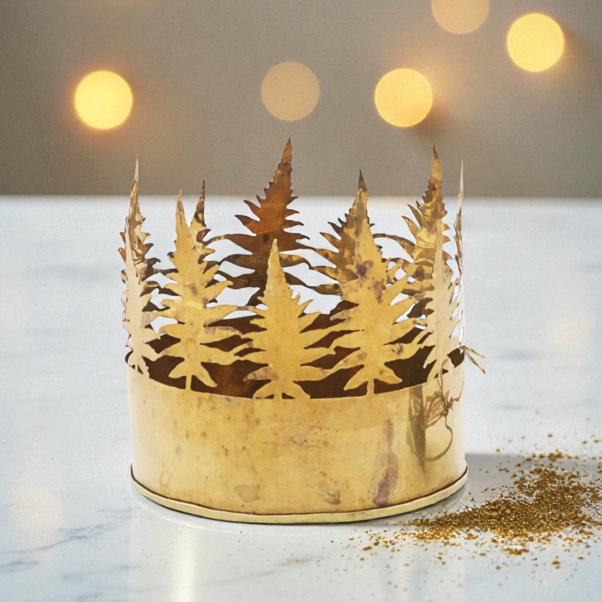 Couronne dorée et découpages d'arbres en papier sur une table, avec des lumières chaudes et floues en arrière-plan