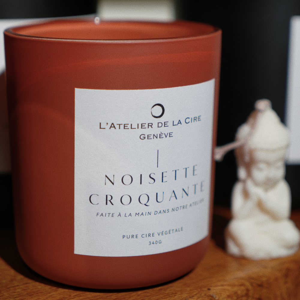 Un ensemble de bougies en verre ambré avec des couvercles noirs et des étiquettes blanches, disposées sur un fond blanc.