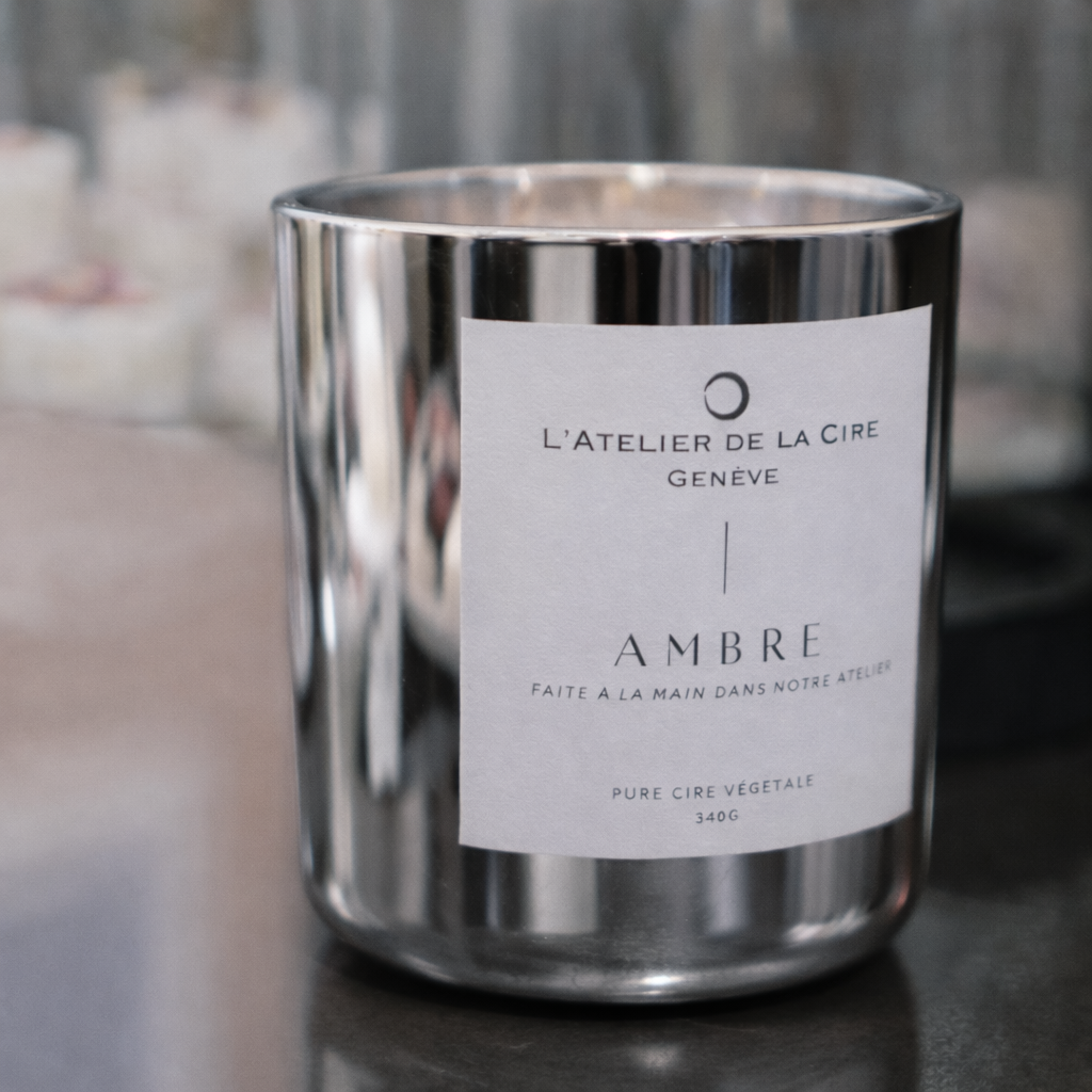 Pot à bougie argenté avec une étiquette blanche portant l'inscription « AMBRE » sur fond gris