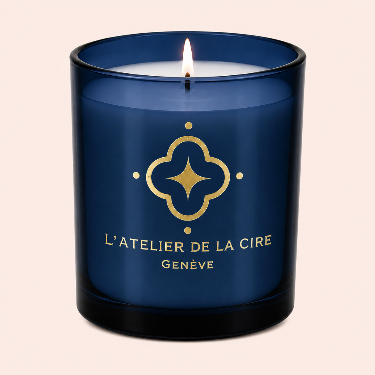 Bougie bleue avec logo et texte dorés, flamme allumée centrée au sommet, portant l'inscription « L'Atelier de la Cire Genève »