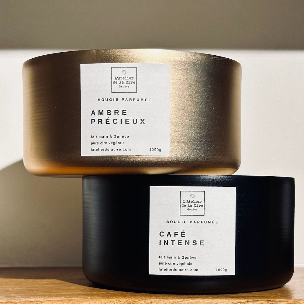 Pot à bougie doré étiqueté « Ambre Précieux » sur fond de pierre beige