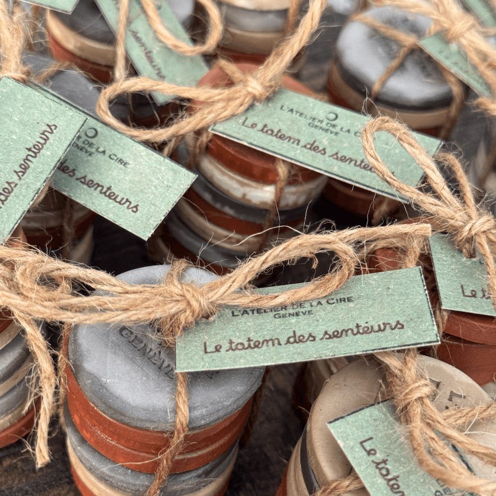 De petits pots attachés avec de la ficelle sur un plateau en bois, avec des étiquettes rondes aux tons pastel éparpillées sur une table rustique.