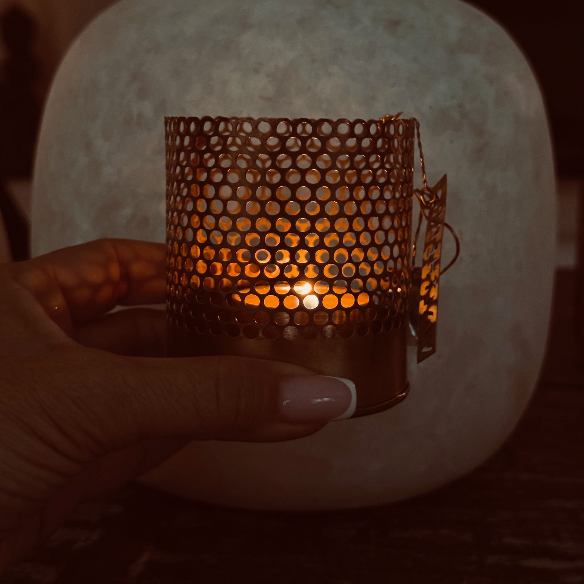 Bougeoirs en verre à lumière chaude avec des motifs ajourés de maisons et de fougères sur une surface sombre