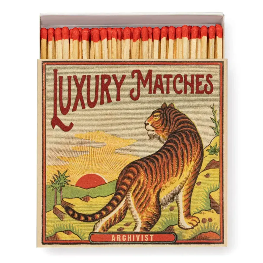 Boîte d'allumettes de luxe vintage ornée d'un tigre et laissant apparaître des allumettes à pointe rouge sur le dessus.