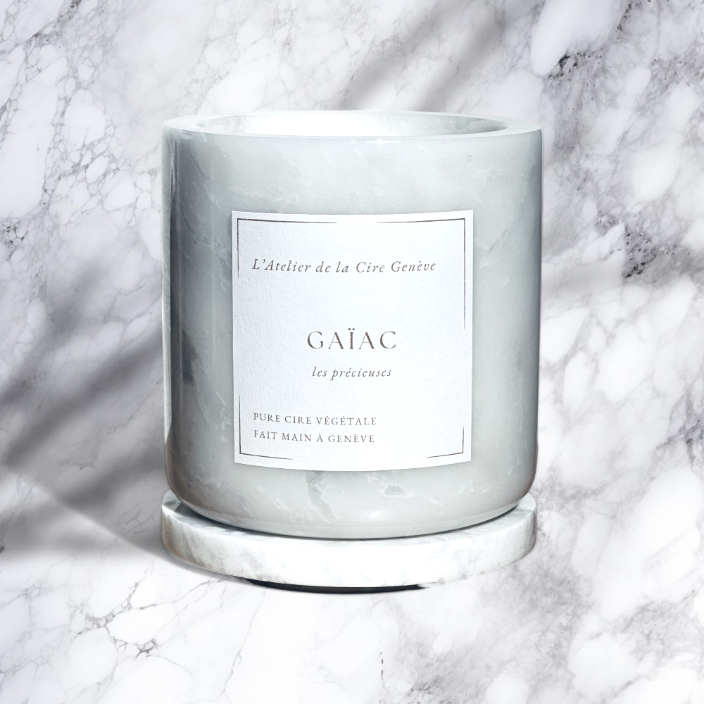 Bougie parfumée gris pâle dans un pot en verre dépoli sur une surface en marbre blanc
