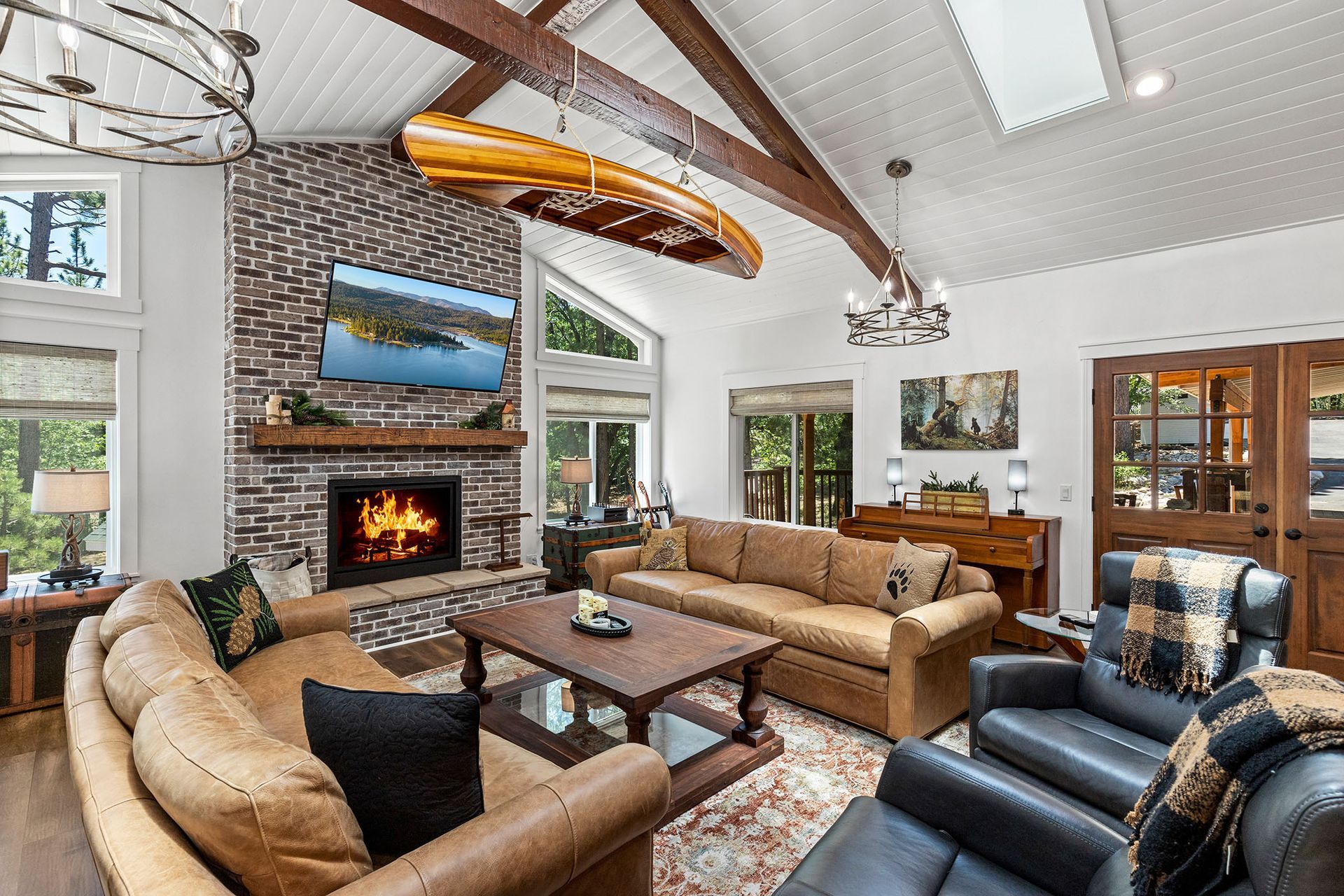 A living room filled with furniture and a fireplace with a canoe hanging from the ceiling.