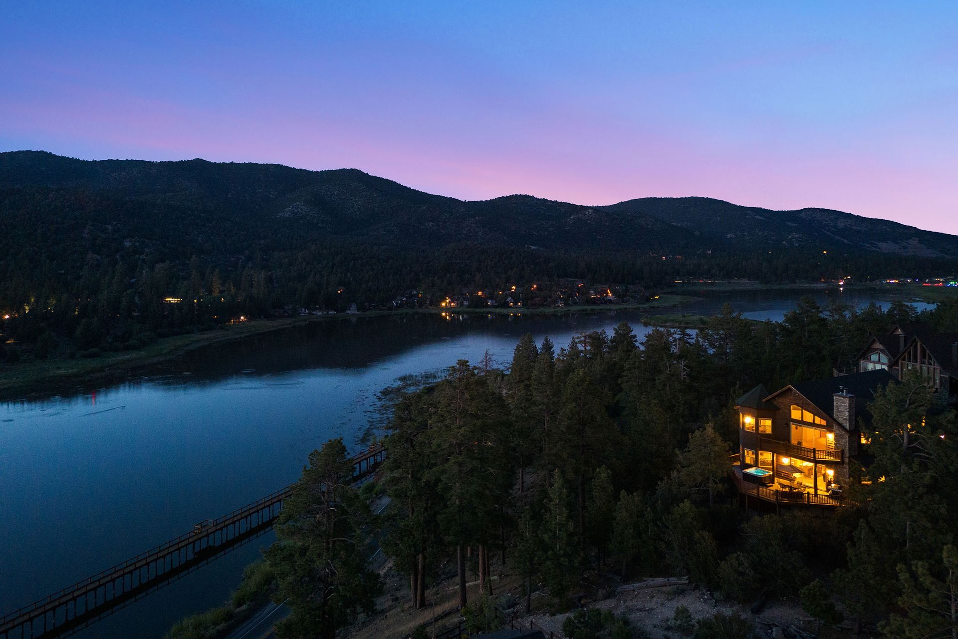An aerial view of a house on a hill overlooking a lake at night.