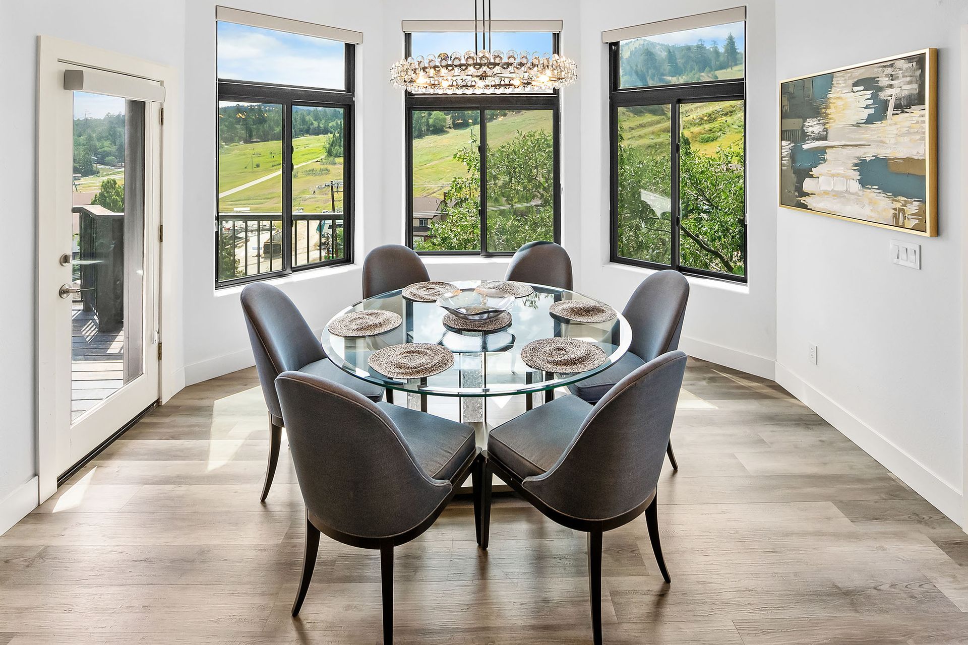 A dining room with a round table and chairs and lots of windows.