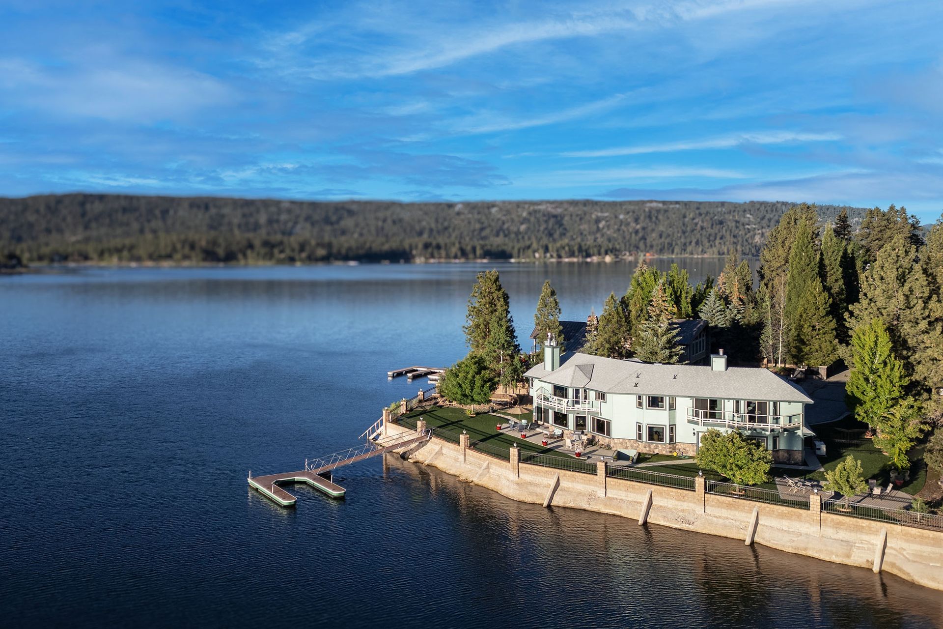 An aerial view of a large house on the shore of a lake.