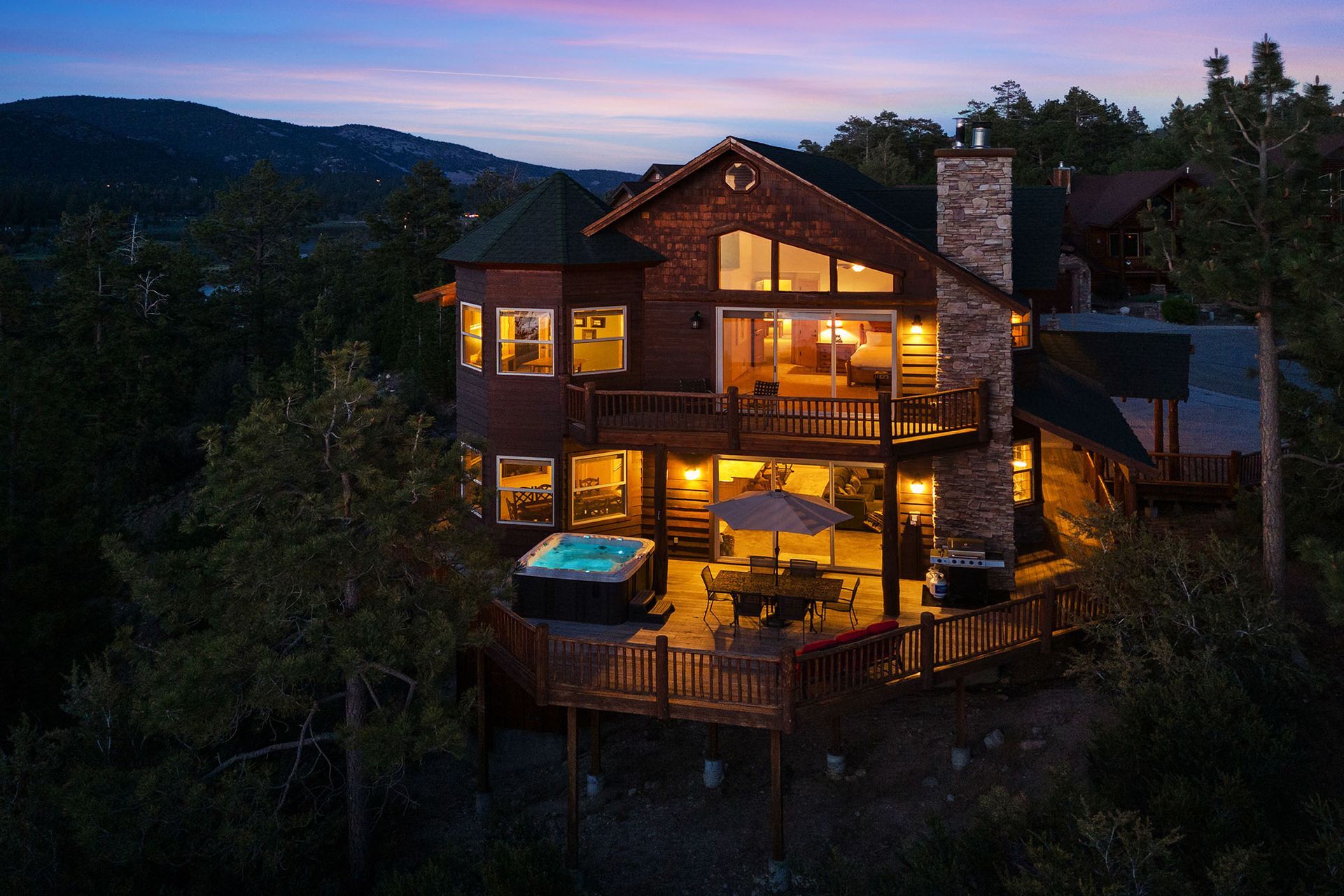 An aerial view of a large house with a hot tub on the deck at night.
