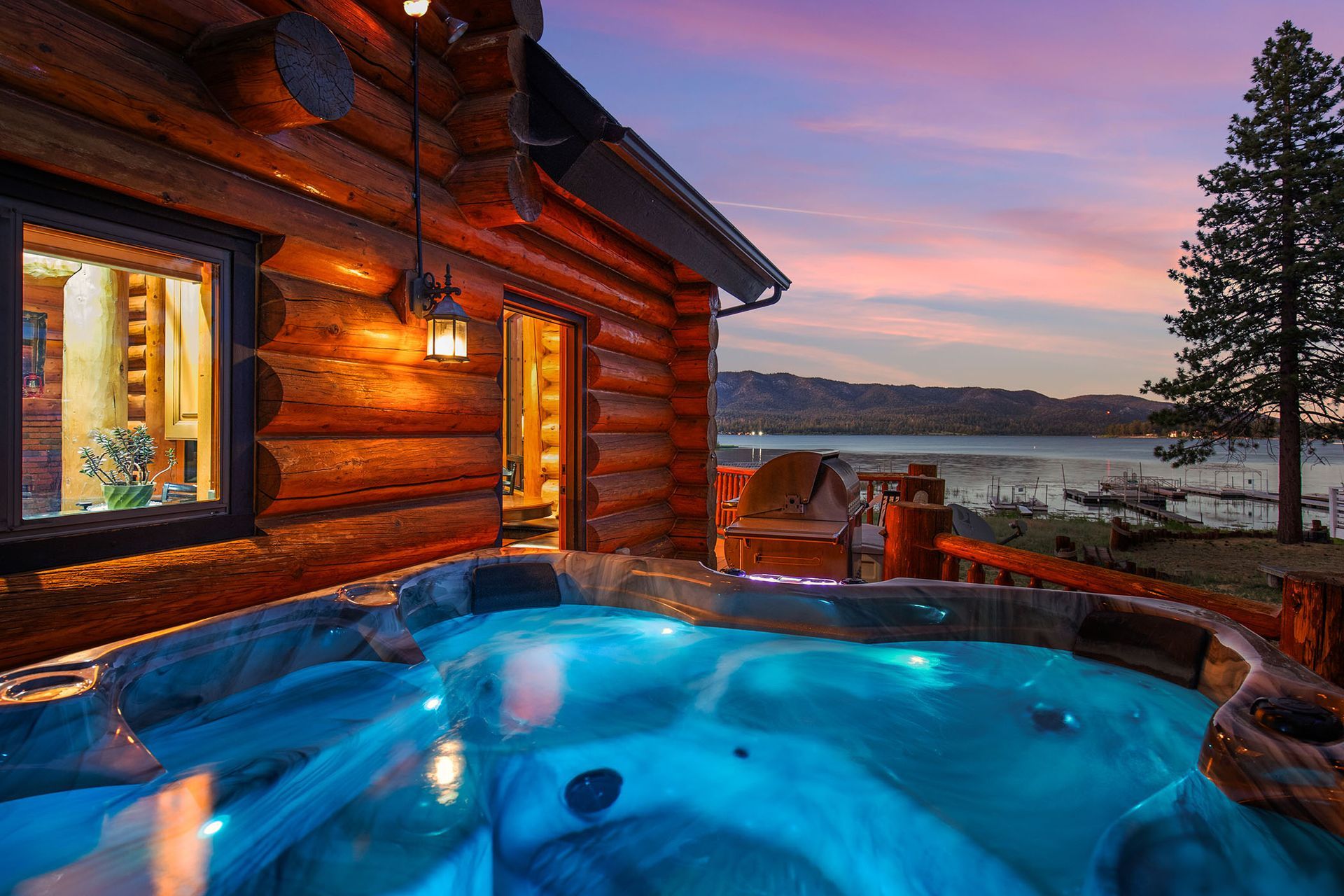 A log cabin with a hot tub in front of it.