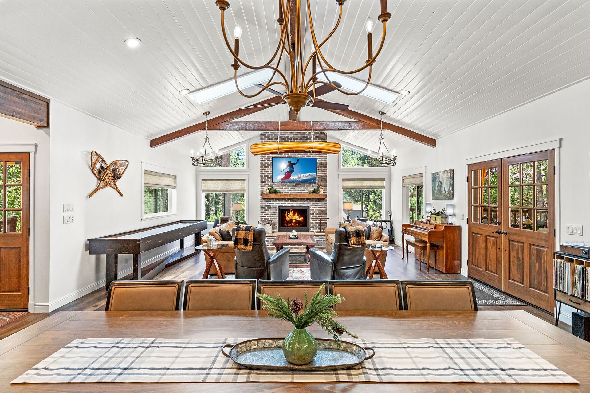 A large living room with a chandelier , a fireplace , and a shuffleboard table.