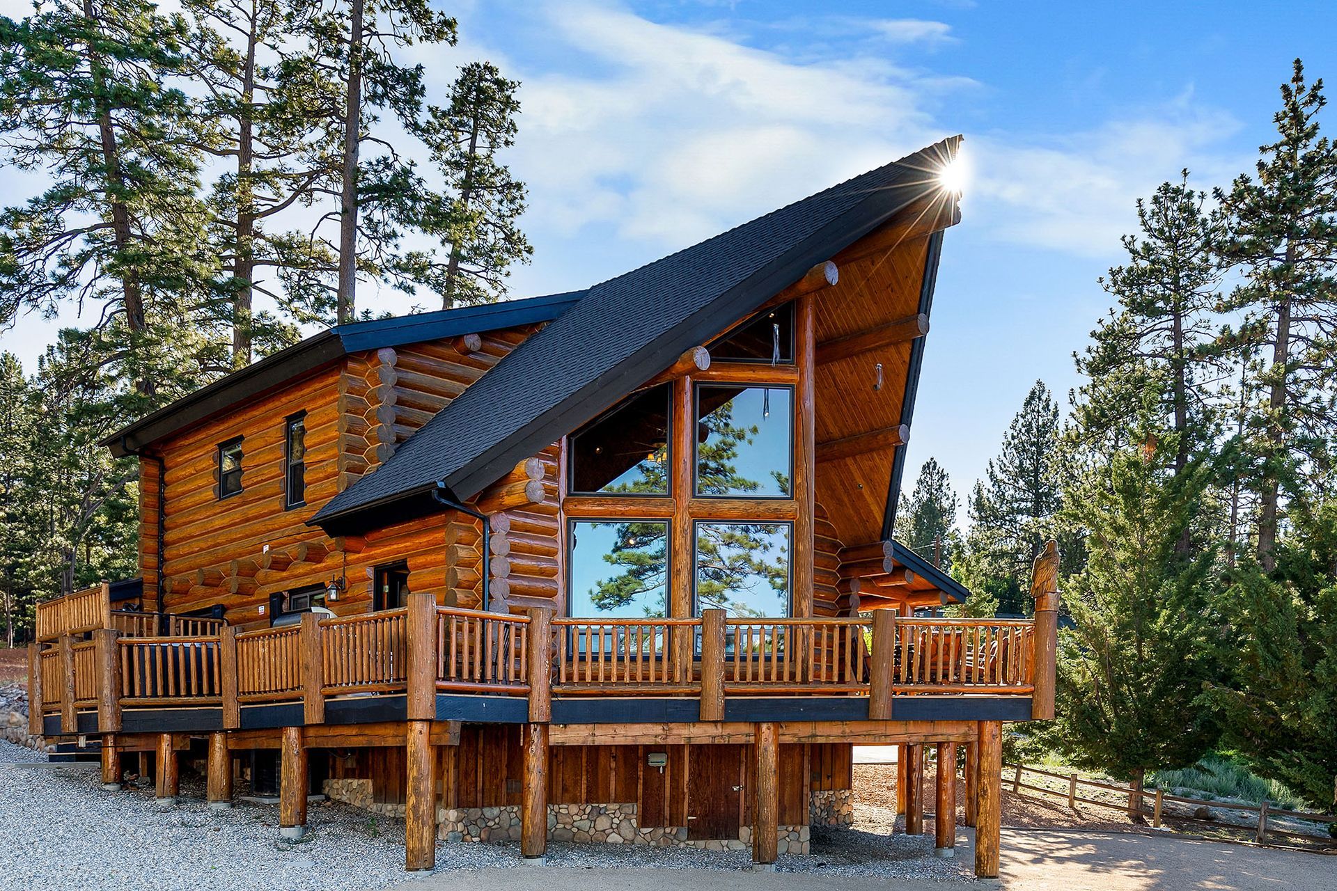 A large log cabin with a large deck in the woods