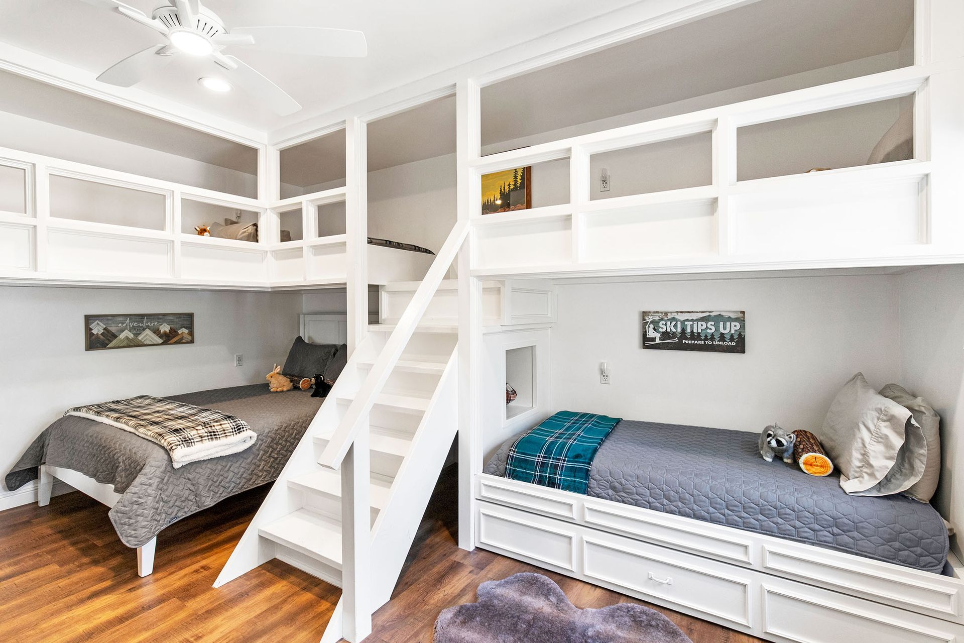 A bedroom with three bunk beds and stairs.