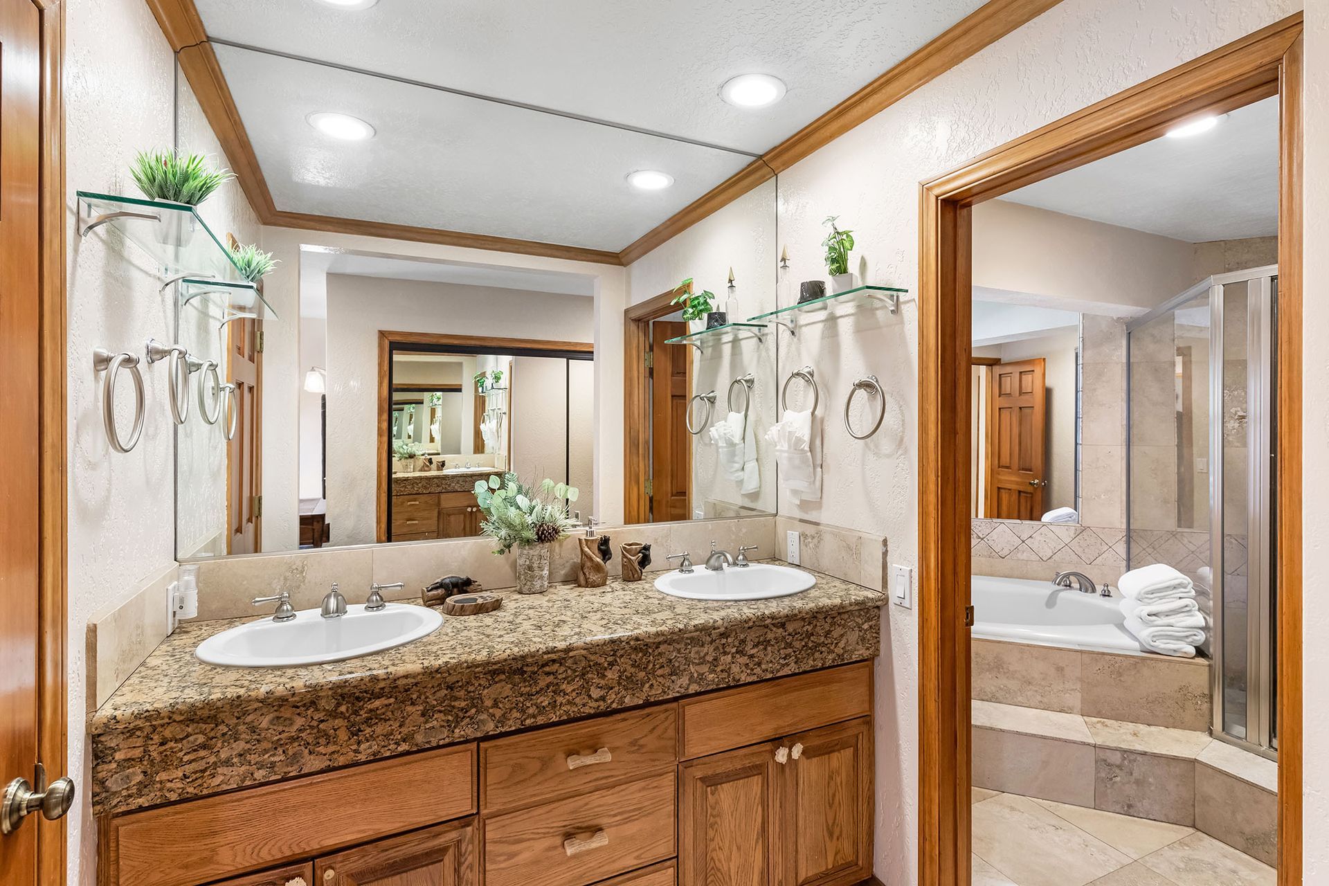 A bathroom with two sinks , a tub and a mirror.