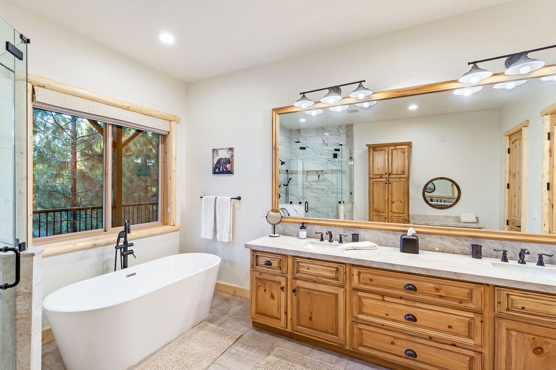 A bathroom with two sinks , a tub , and a large mirror.