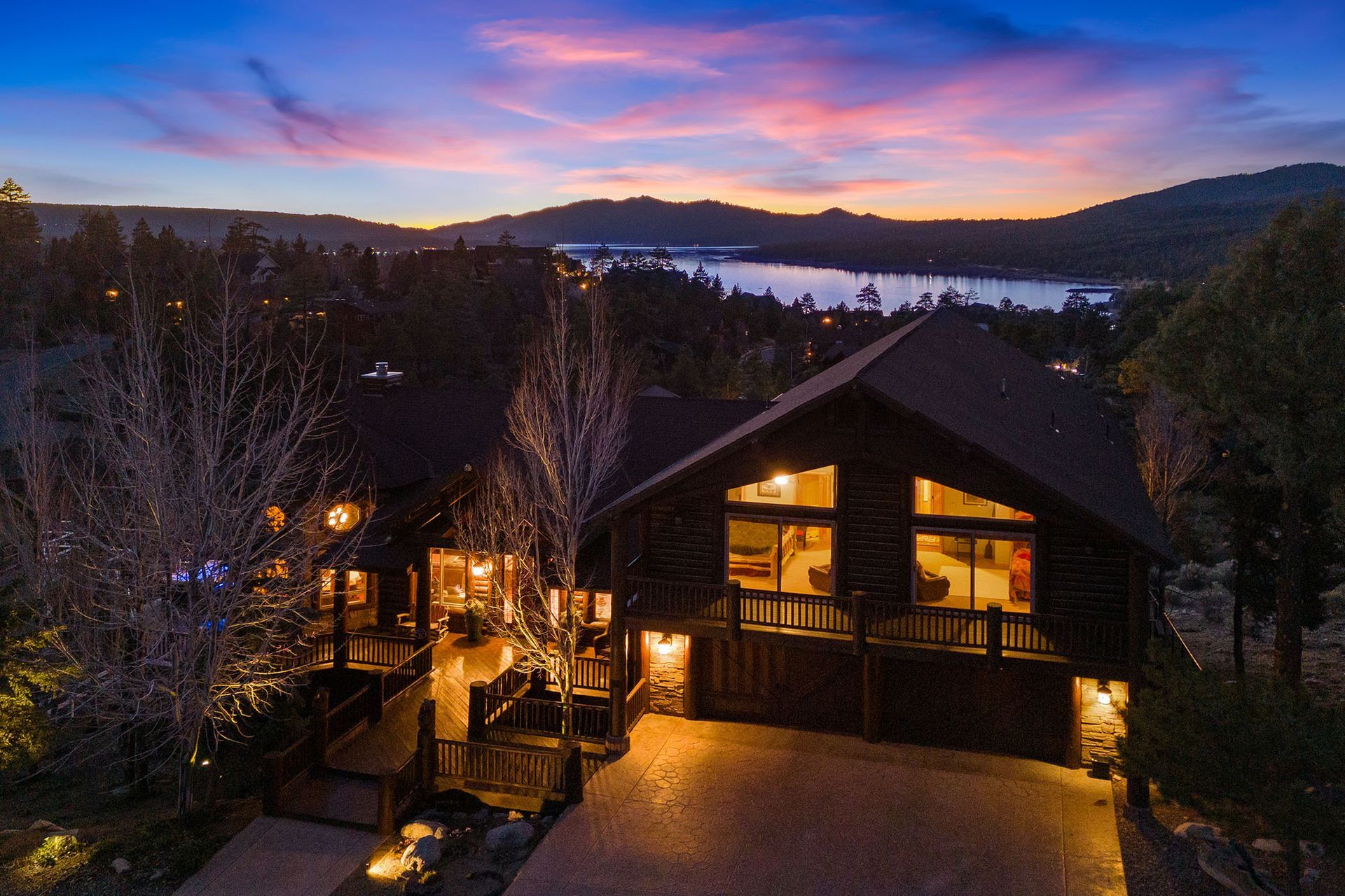 An aerial view of a large house with a lake in the background at sunset.