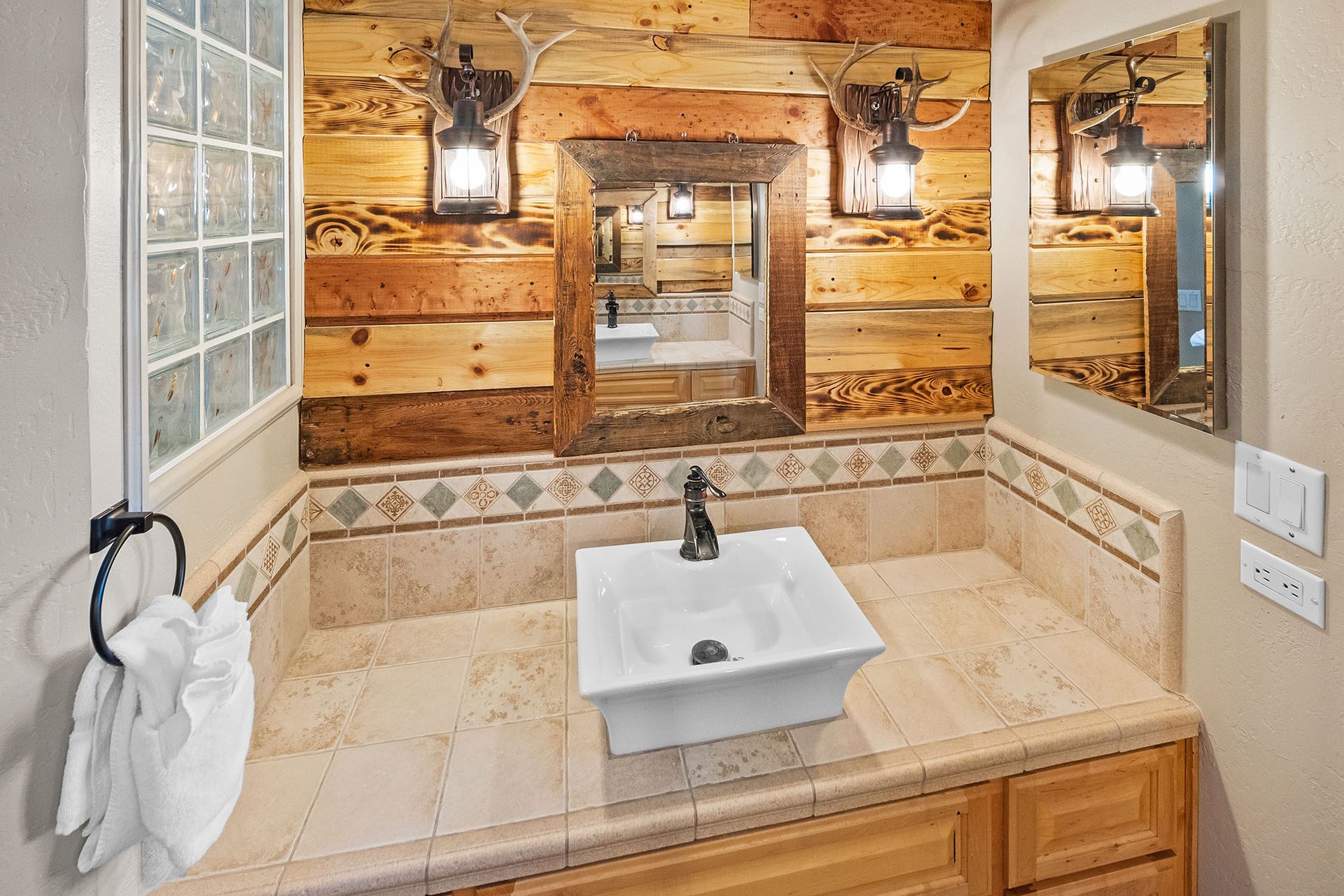A bathroom with a sink , mirror and wooden walls.