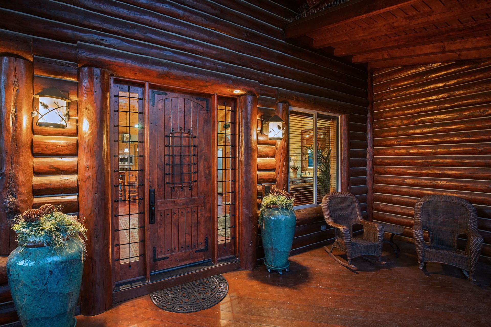 A log cabin with a large wooden door and potted plants in front of it.
