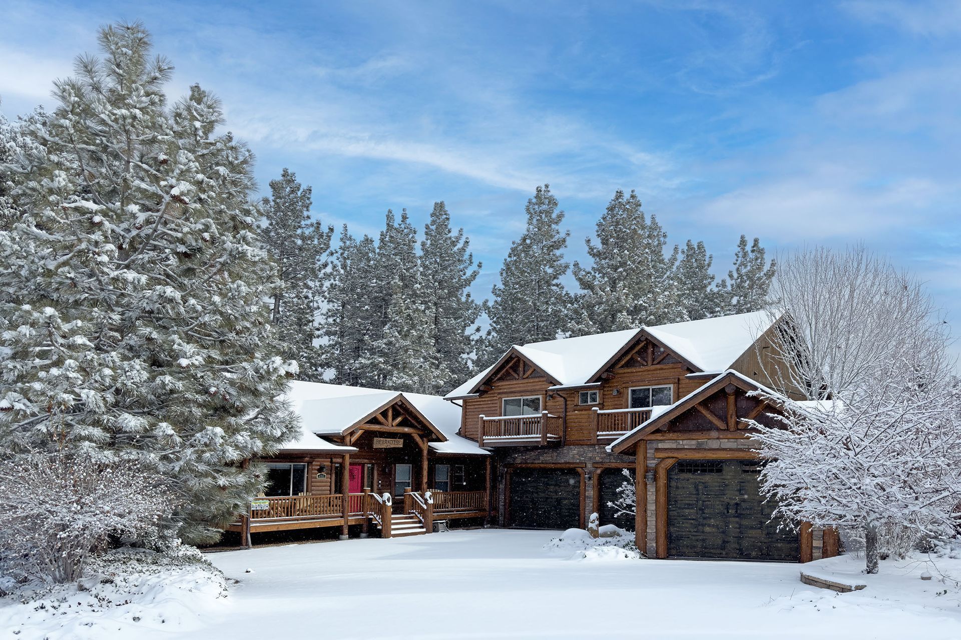A large house is surrounded by snow covered trees