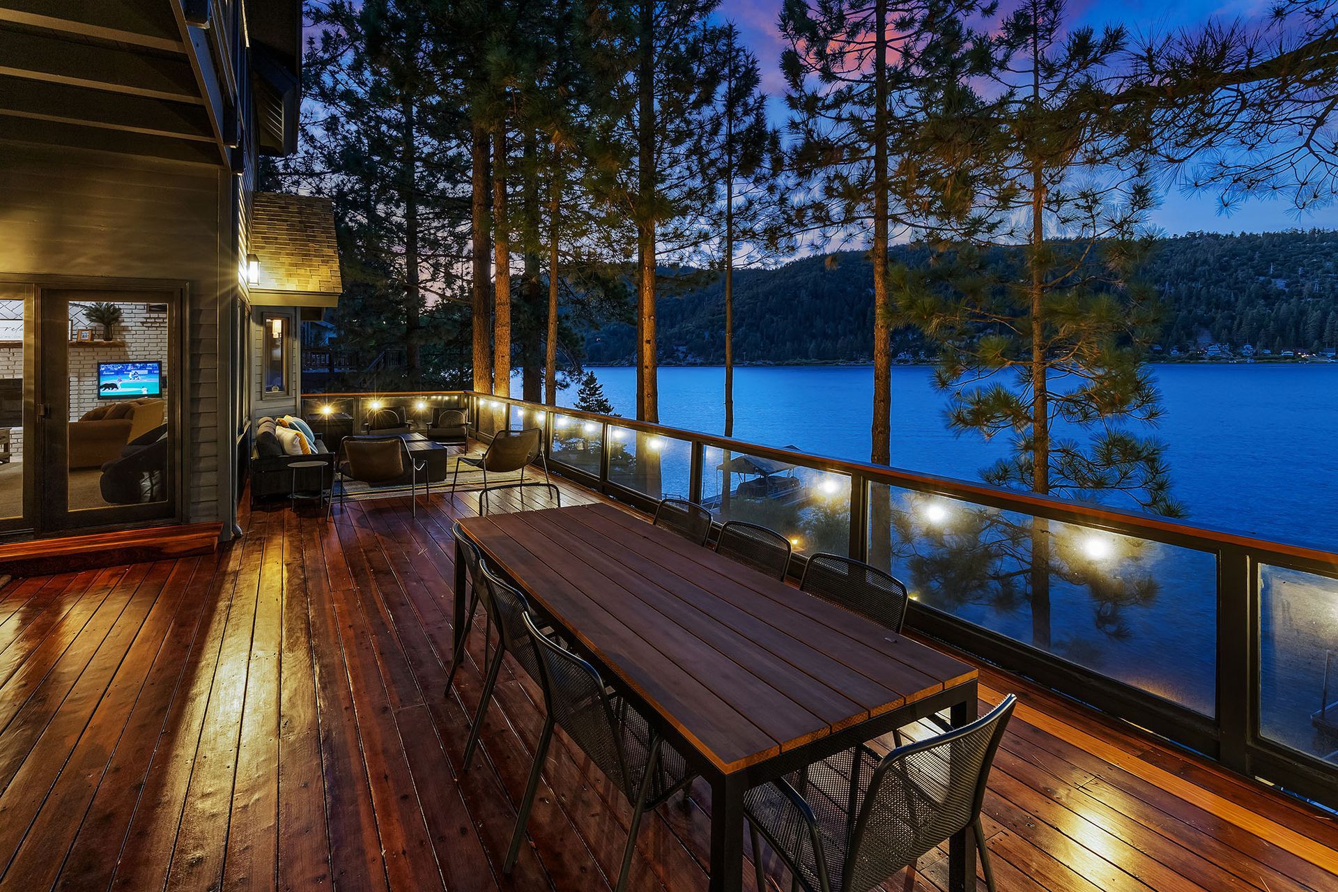 A large wooden deck with a table and chairs overlooking a lake.