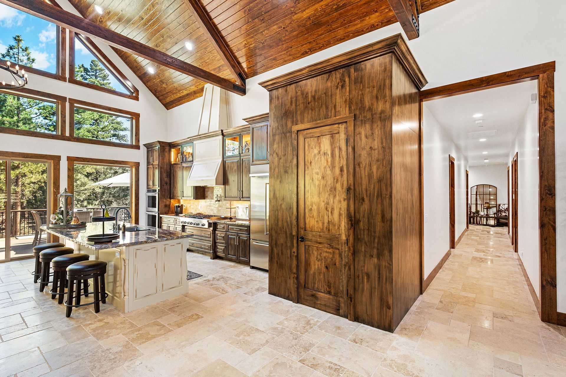 A large kitchen with a wooden ceiling and stools in a house.
