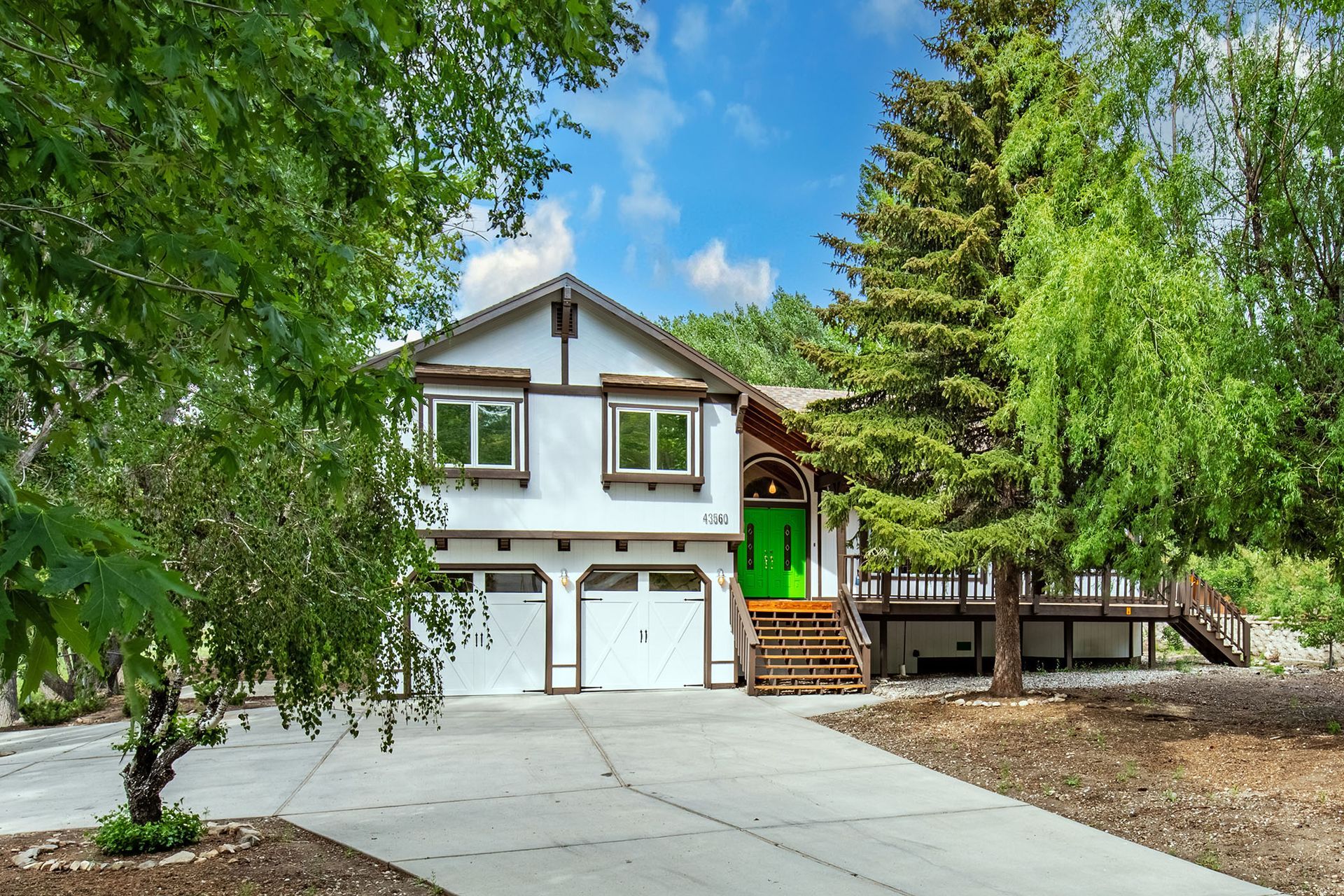 A white house with a green door is surrounded by trees