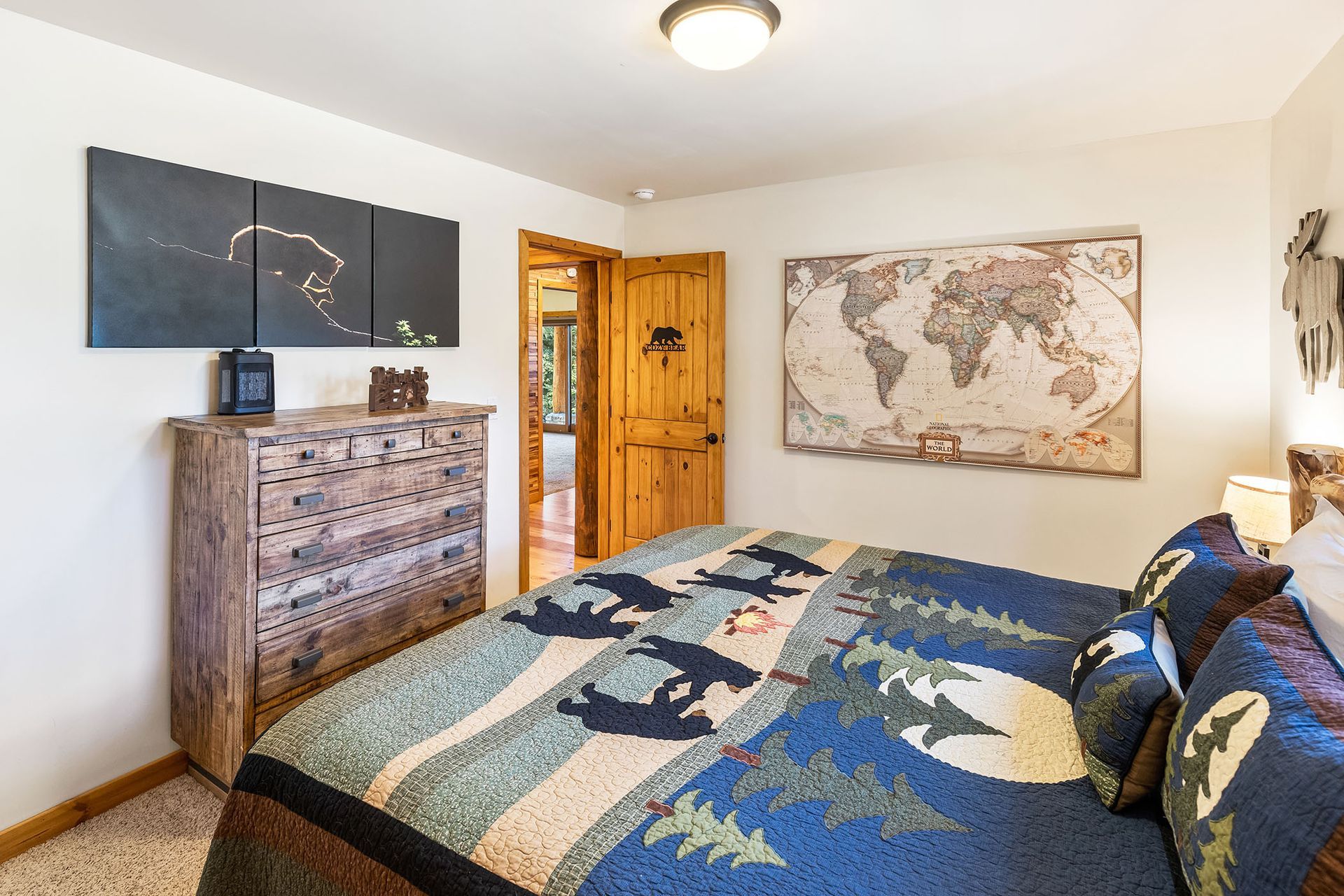 A bedroom with a large bed , dresser , and map on the wall.