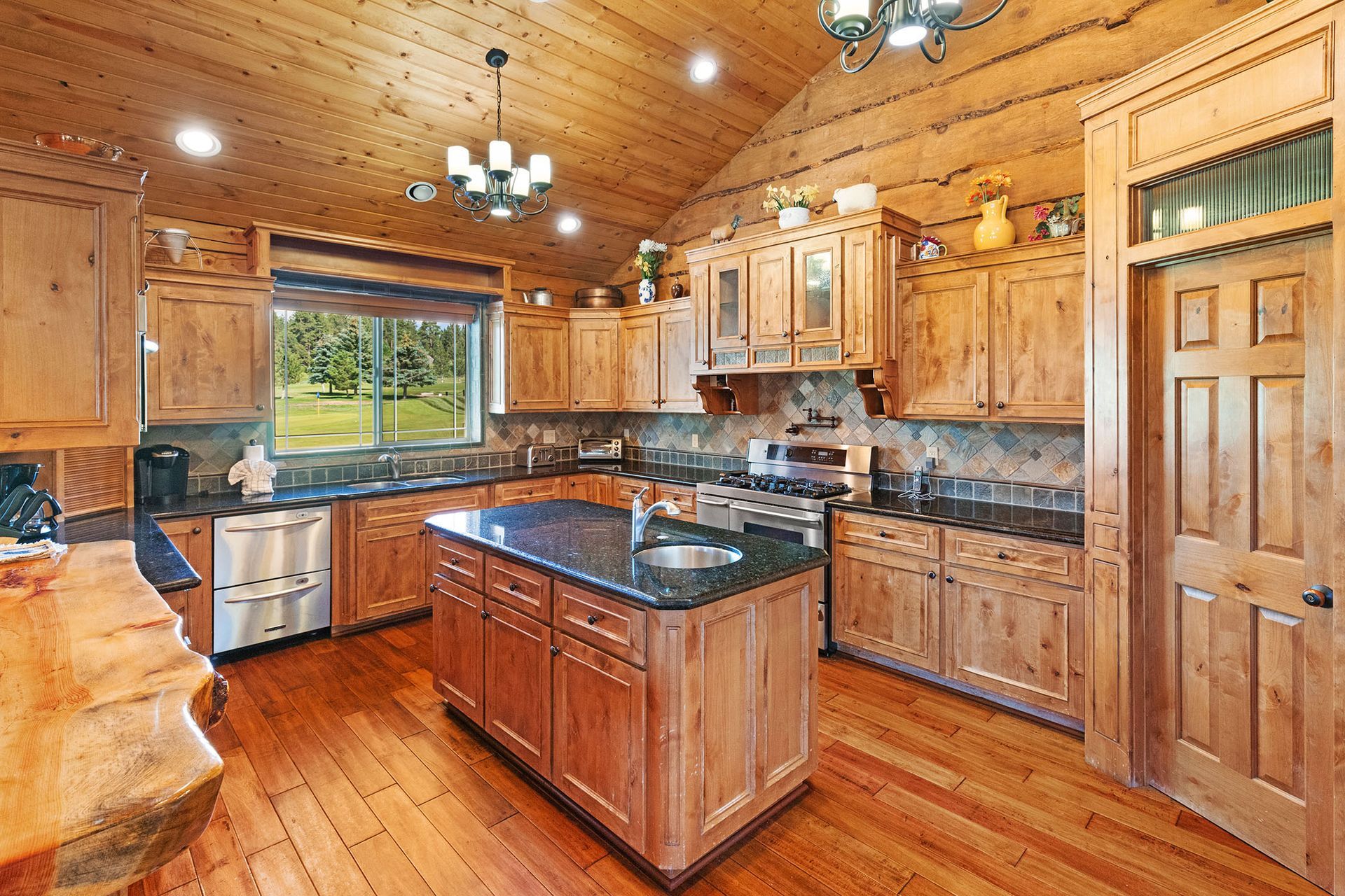 A kitchen in a log cabin with wooden cabinets and granite counter tops