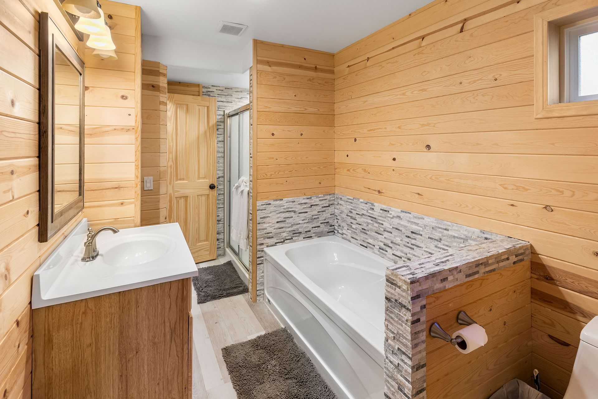 A bathroom with a bathtub , sink , toilet and mirror.