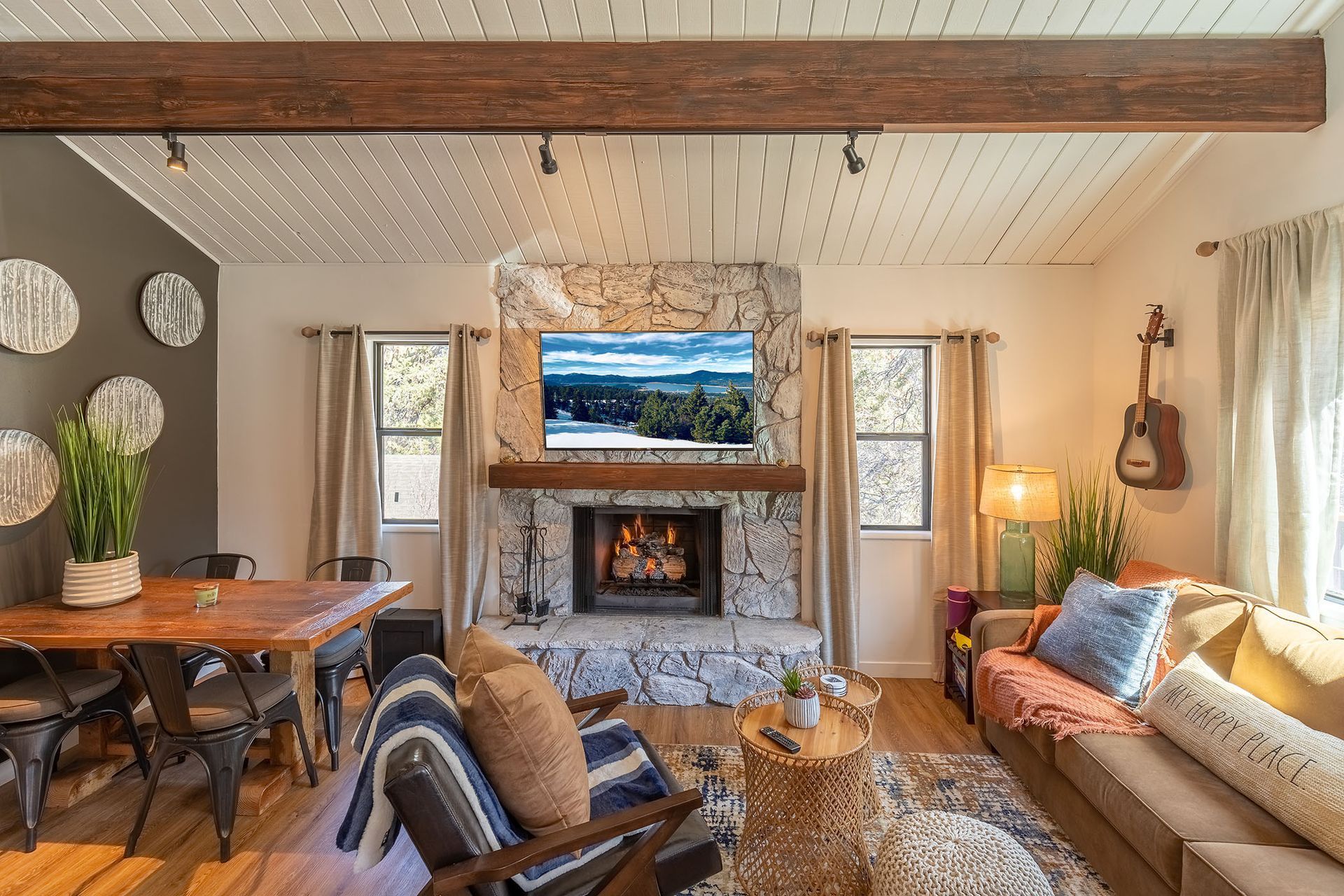 A living room with a fireplace , couch , chair , table and television.