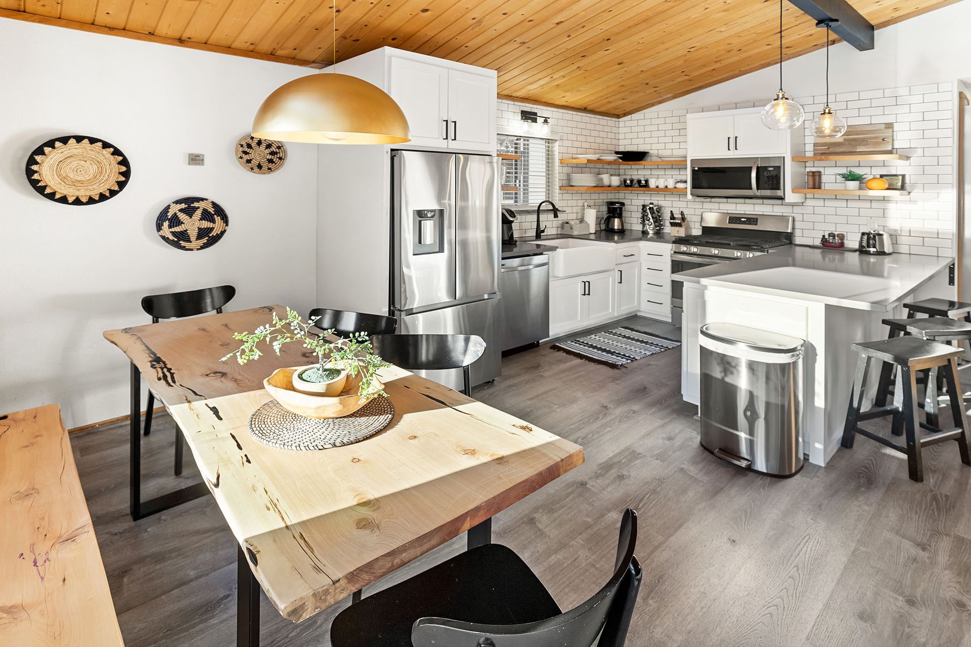A kitchen with a wooden table and chairs and a wooden ceiling.