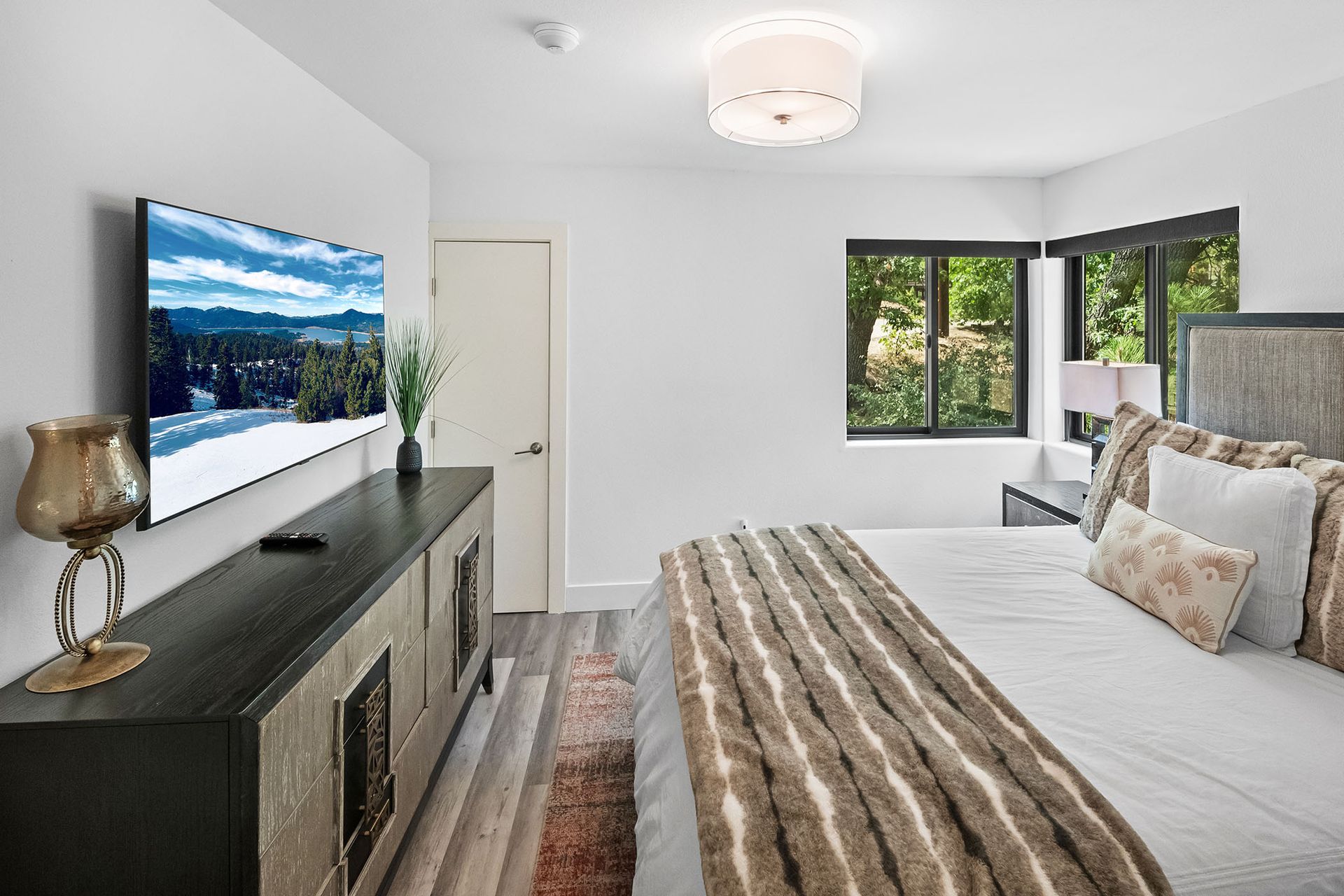 A bedroom with a large bed and a flat screen tv on the wall.