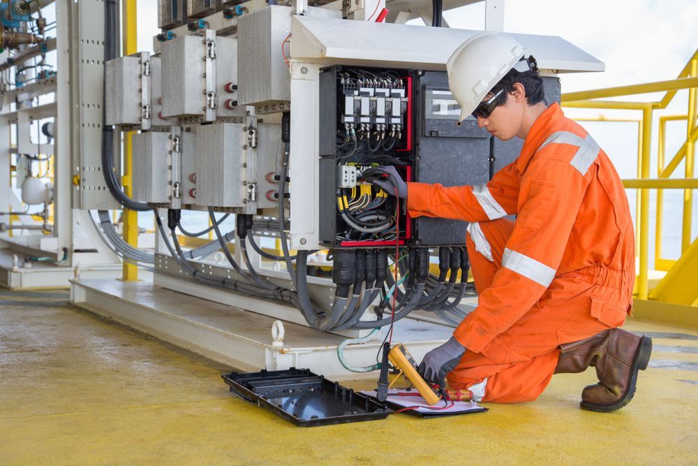 A Man In An Orange Jumpsuit Is Working On A Machine — Keany's Electrical Service In North Nowra, NSW