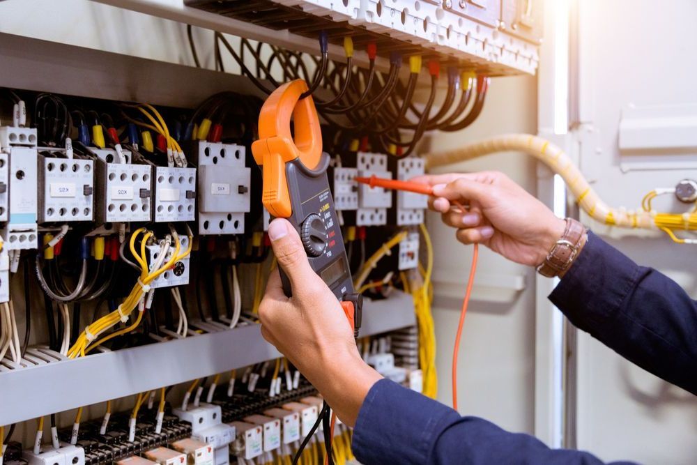 An Electrician Is Working On An Electrical Panel With A Clamp Meter — Keany's Electrical Service In South Nowra, NSW