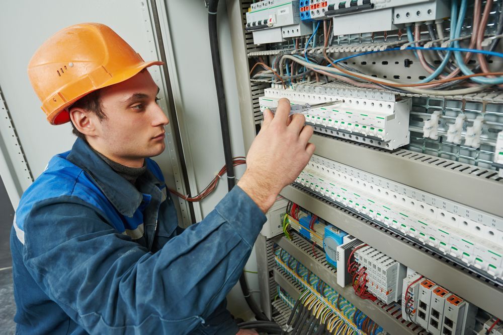 A Man Wearing A Hard Hat Is Working On An Electrical Box — Keany's Electrical Service In North Nowra, NSW