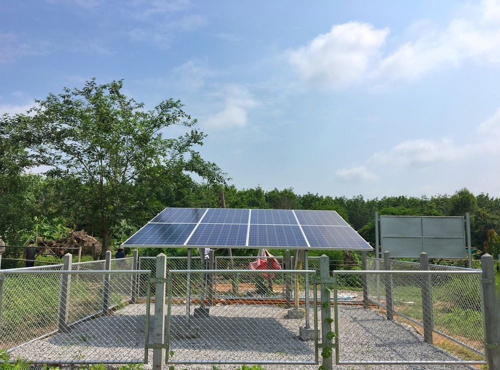 A Group Of Solar Panels Are Sitting Under A Fence In A Field — Keany's Electrical Service In North Nowra, NSW