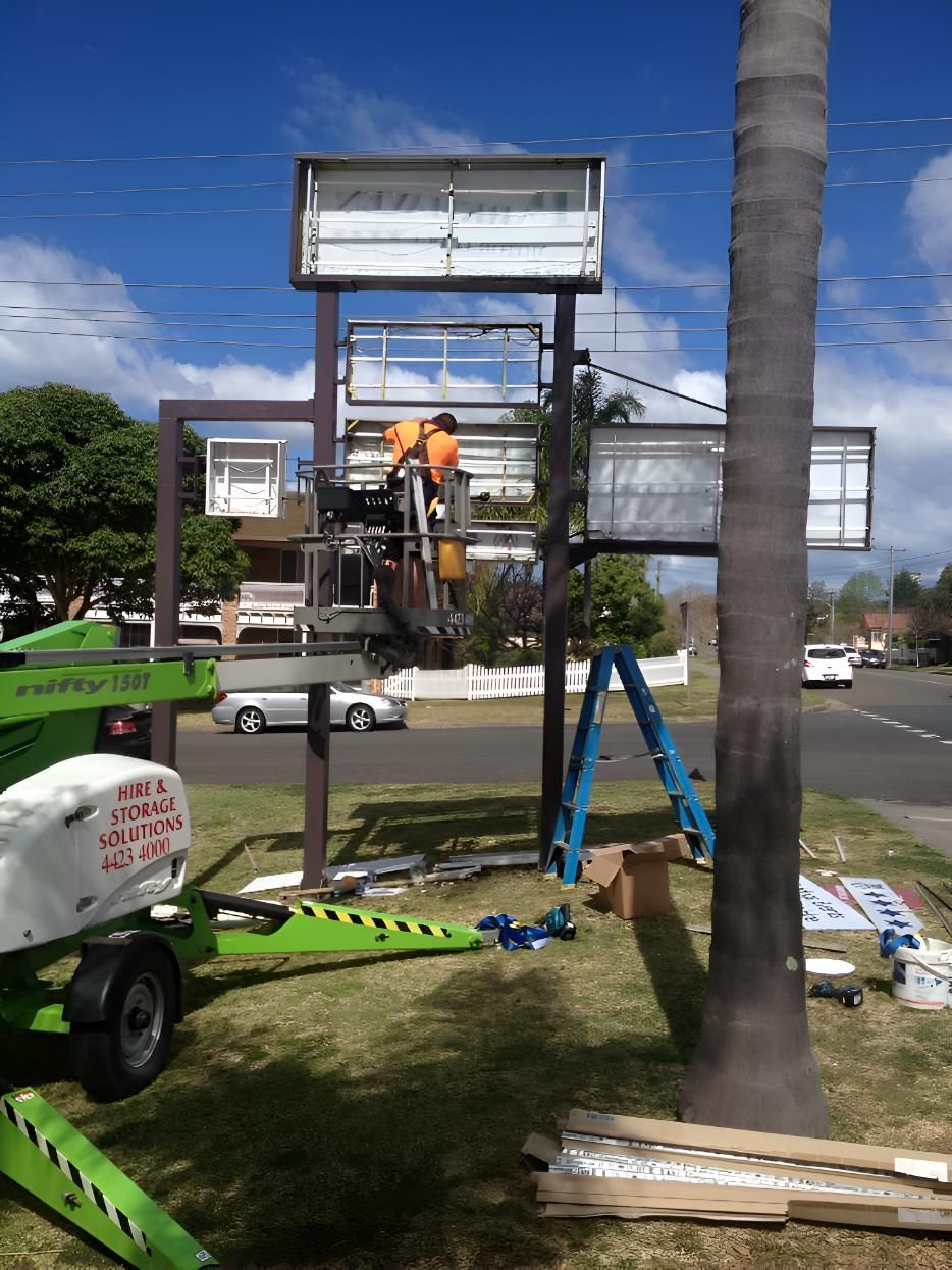A Man On A Lift Is Working On A Billboard — Keany's Electrical Service In North Nowra, NSW