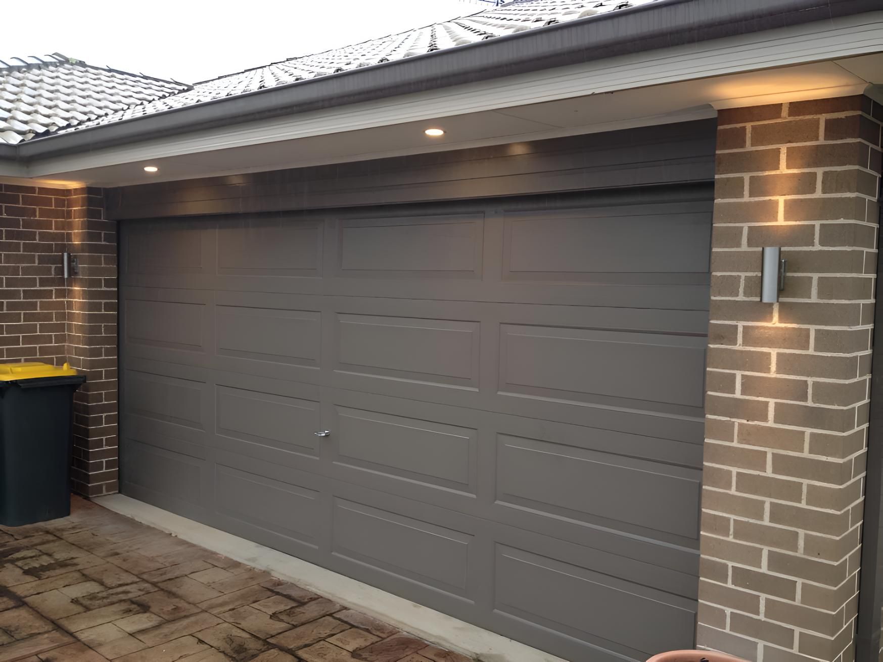 A Gray Garage Door Is Sitting Next To A Brick Wall — Keany's Electrical Service In North Nowra, NSW
