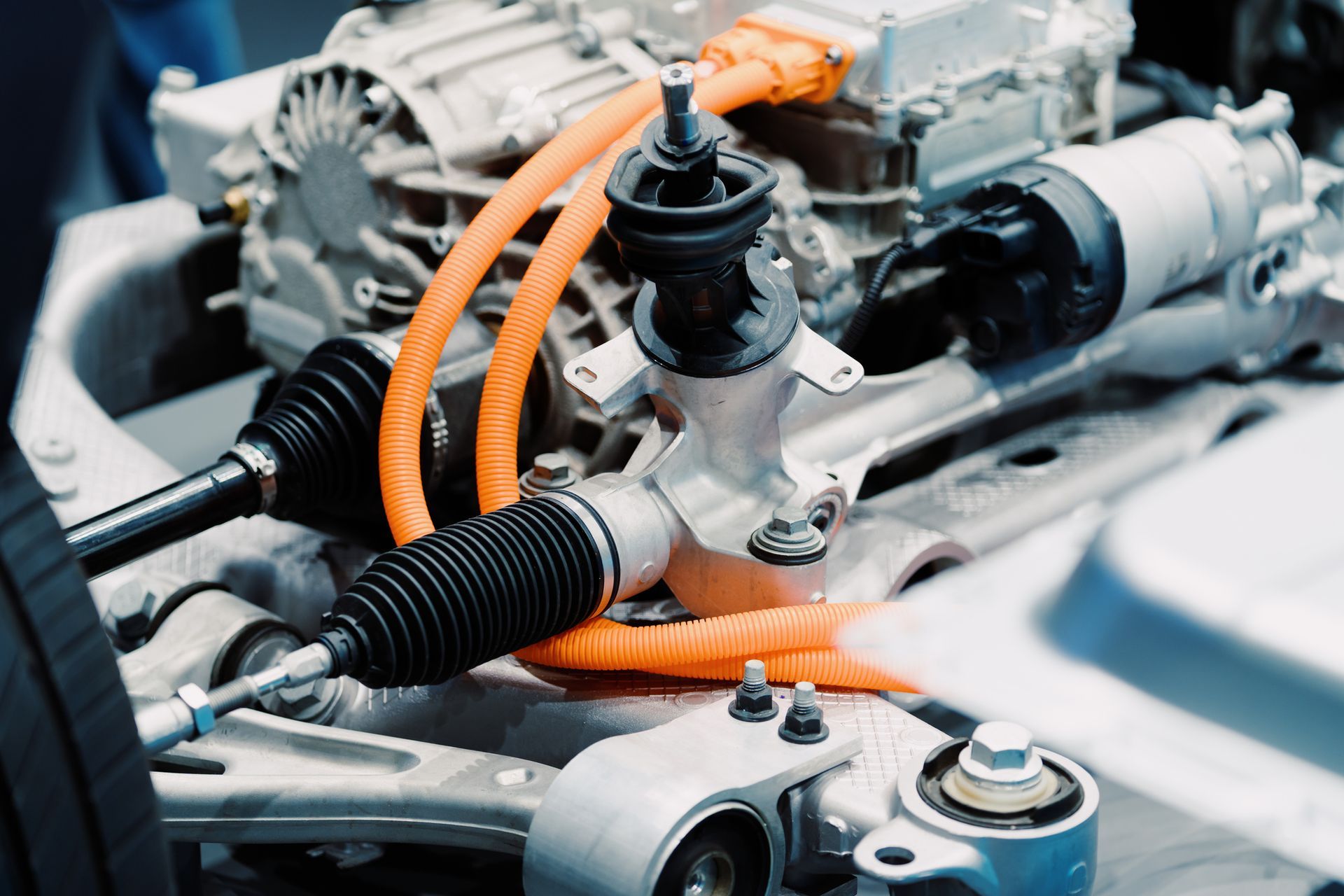 A close up of a car engine with orange wires coming out of it.