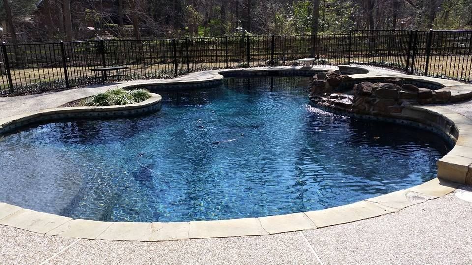 A large swimming pool with a fence around it in a backyard.