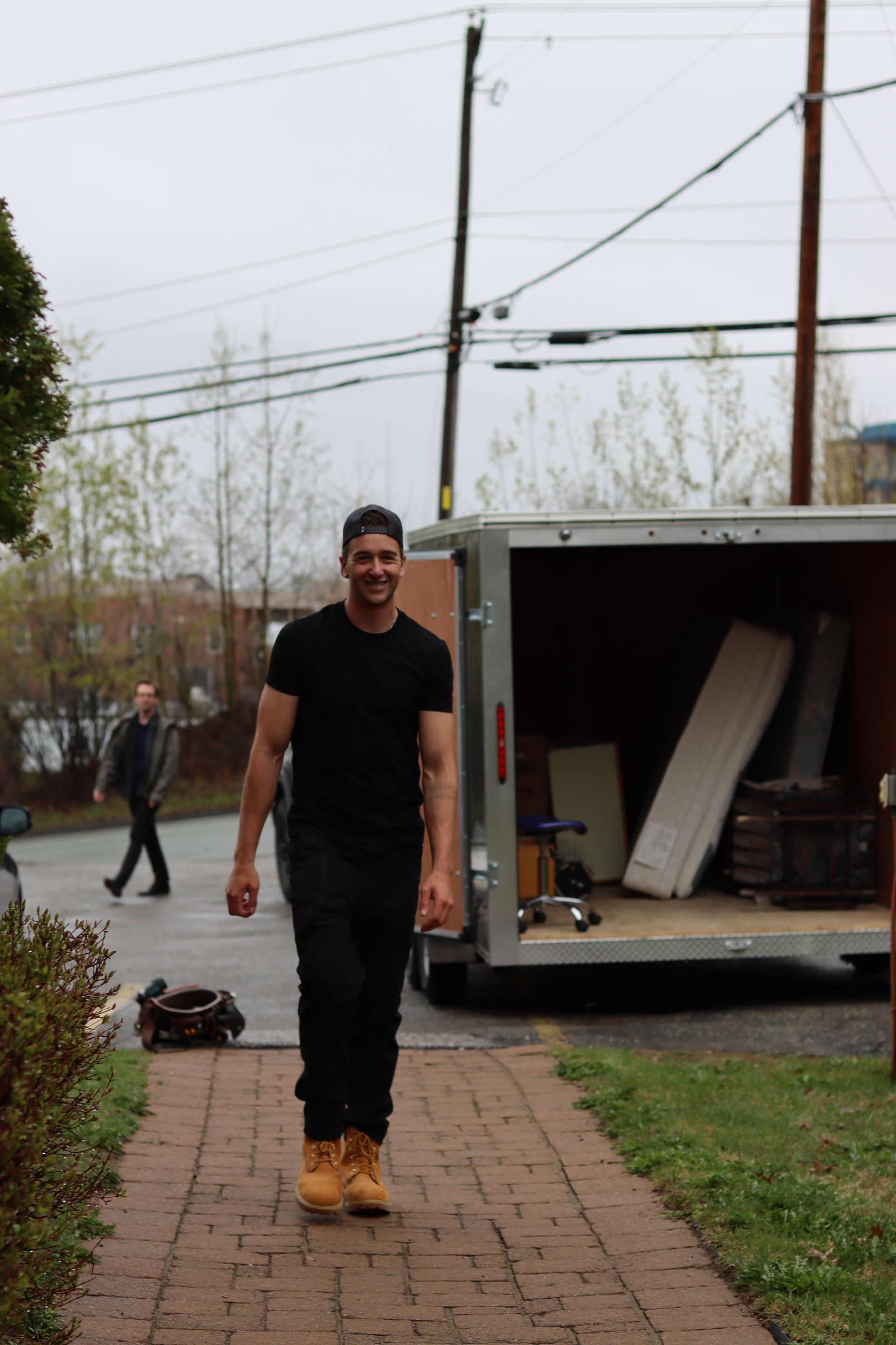 Un homme marche sur un chemin de briques à côté d'une remorque de déménagement ouverte dans une cour