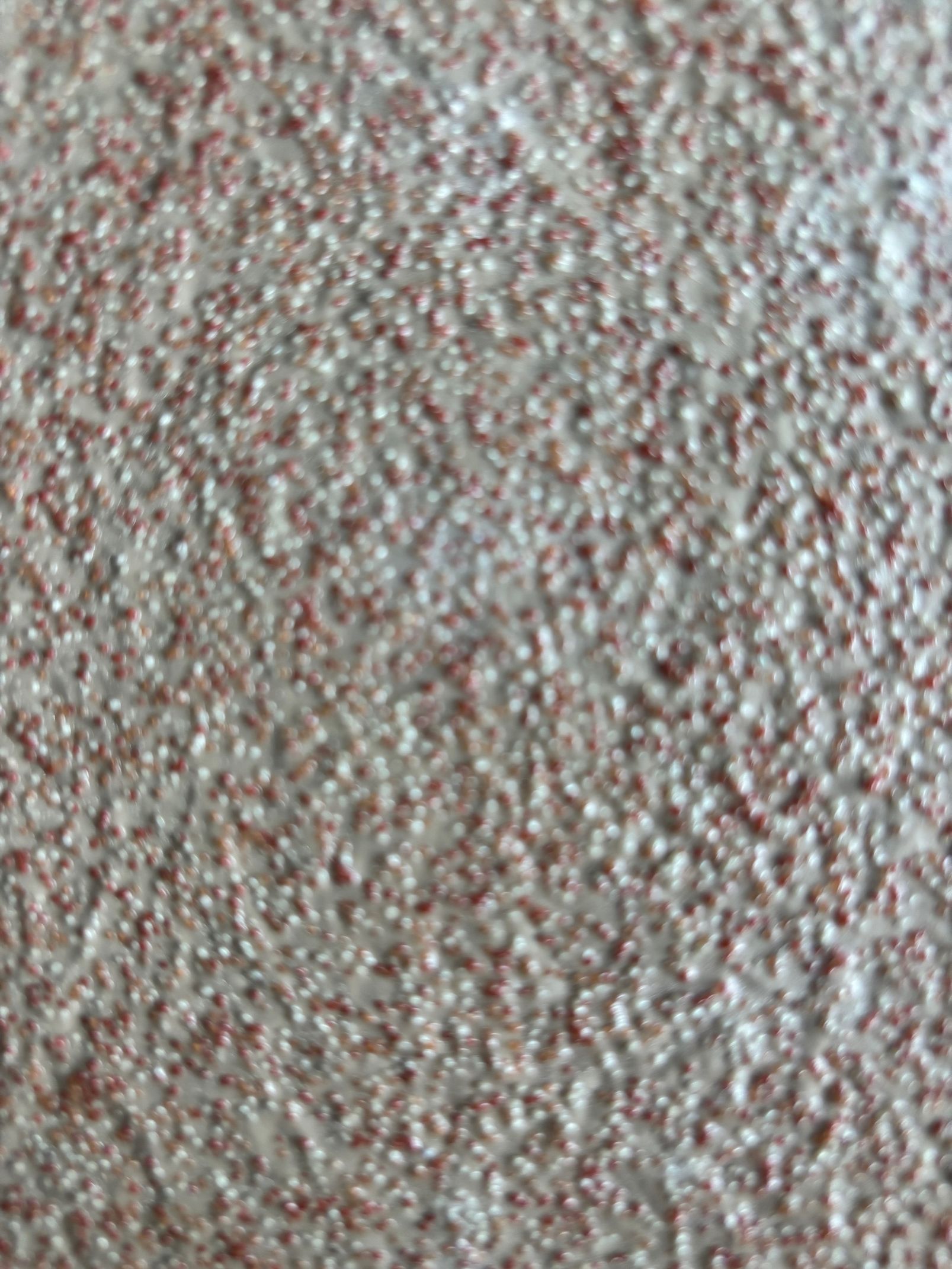 Surface texturée à motif moucheté dans des tons de gris et de brun rougeâtre.